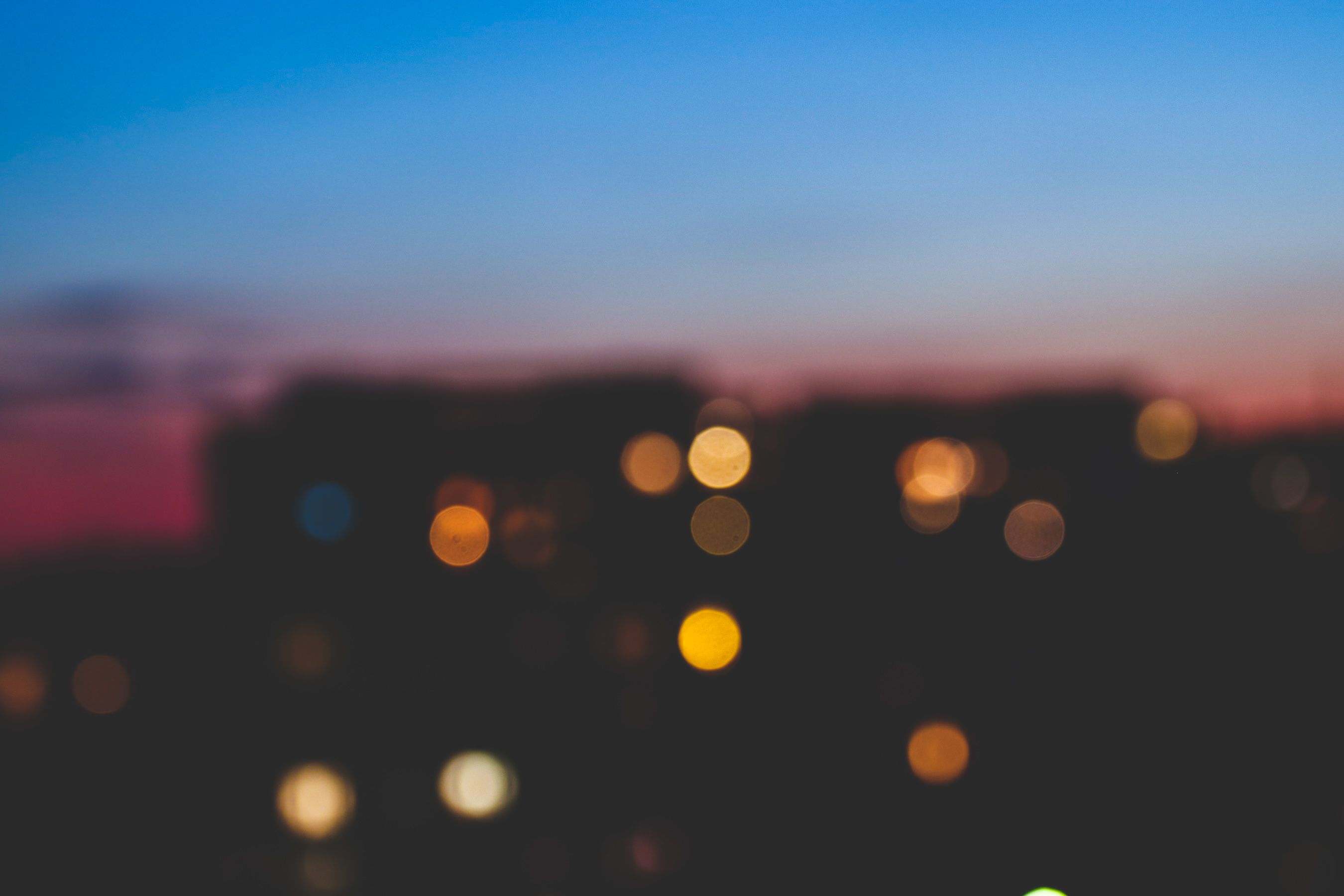 Out-of-focus city lights glowing beneath a blue and pink evening sky.